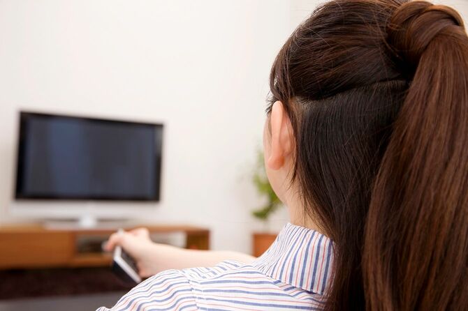 テレビをリモコン操作する女性