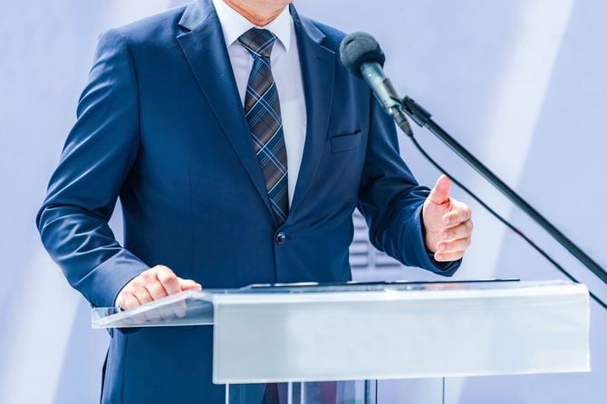 マイクに向かって話しているスーツ姿の男性