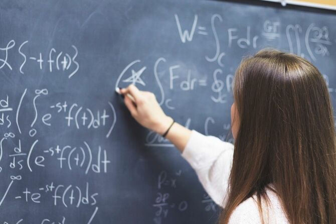 黒板に数式を書いていく女性