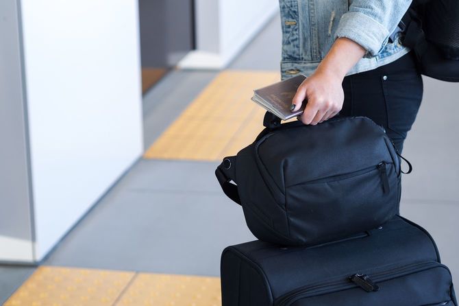 パスポートとスーツケースを持ち、列に並ぶ人