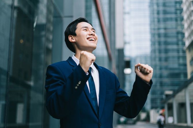 ビジネス街を背景にガッツポーズをするビジネスマン