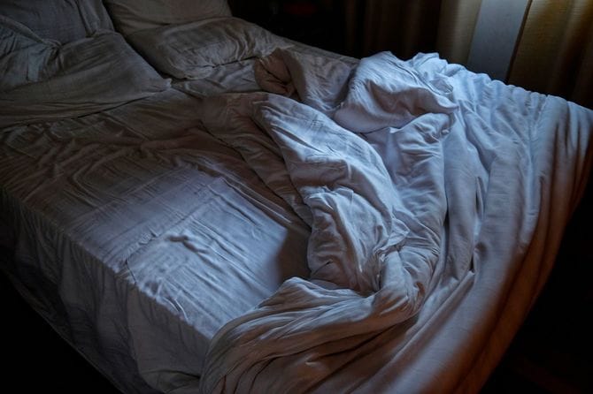 夜明けの整えられていないベッド