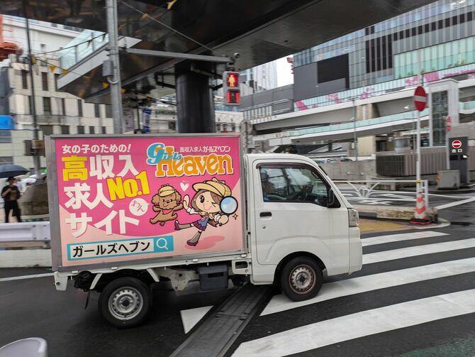 A car advertising a sex industry job site driving through the streets of Shibuya