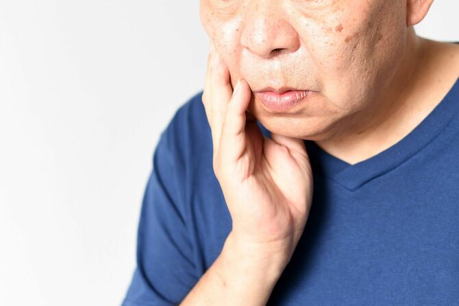 歯のあたりをおさえる高齢男性