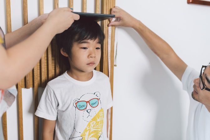 子供の成長をうれしそうに自宅に刻む両親