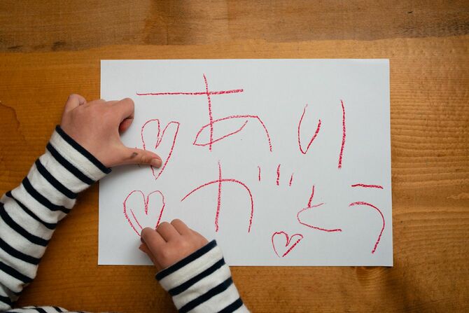 画用紙に子供が赤のクレヨンで「ありがとう」のメッセージ