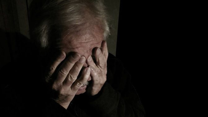 暗い部屋で泣く年配の男性
