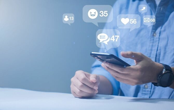 スマートフォンを使用して絵文字や通知ポップアップでソーシャルメディアを再生する男性の手