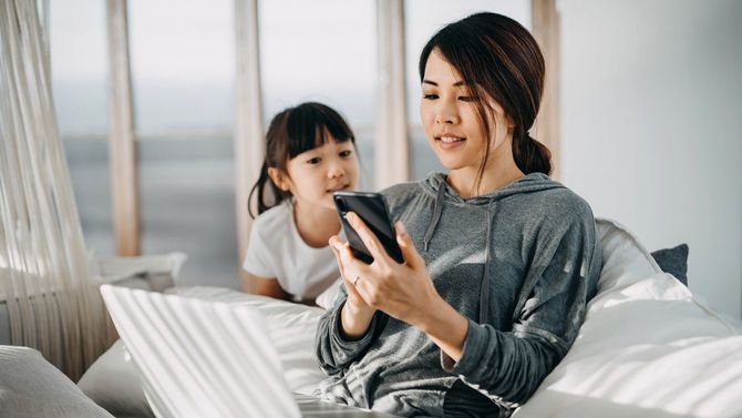 忙しい母親はかまってほしい子供がそばにいてもスマホを操作し、ノートパソコンも使用している