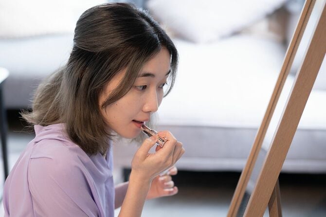 鏡を見ながら口紅を塗る若い日本人女性