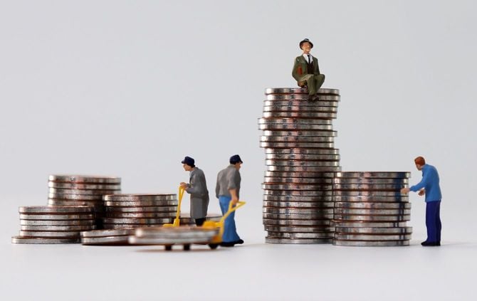コインを運ぶミニチュアの人々とコインの上に座っているミニチュアの男