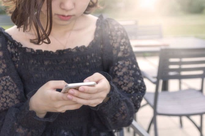 カフェでスマホを使うティーンエージャー