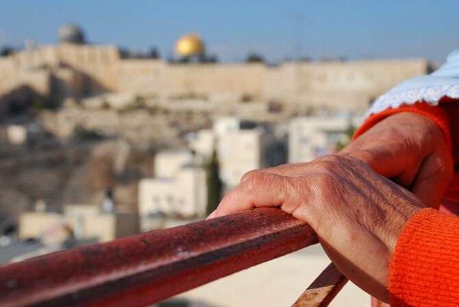 手すりをつかむ女性の手とエルサレムの旧市街