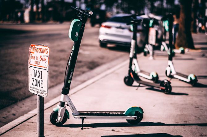 歩道の隅に並べて置かれたレンタル電動キックボード