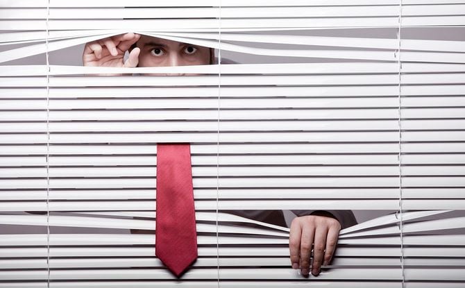 ブラインドの向こうからのぞき込む男性