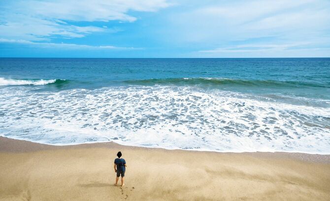 海の砂浜に一人で立っている人