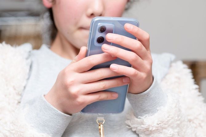 家でスマホを見ている女の子