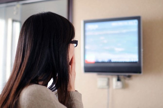 テレビの放送内容にショックを受けている女性