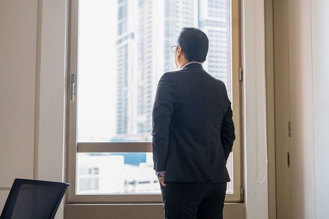 窓から外を見ているビジネスパーソン