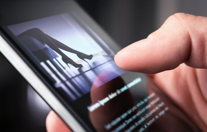 スマートフォンでハイヒールの女性の写真を見ている男性