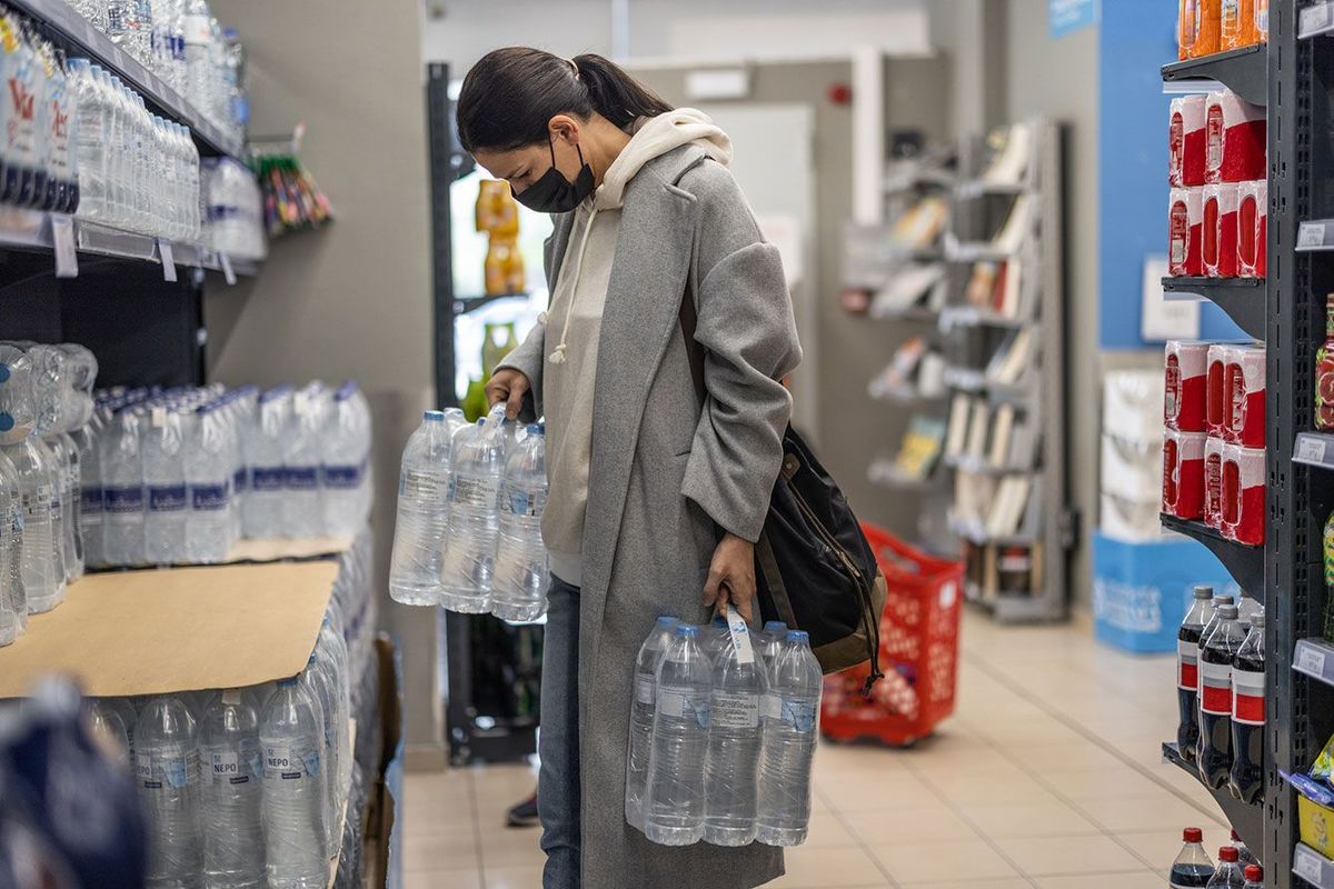 スーパーでペットの水のボトルを選ぶ女性