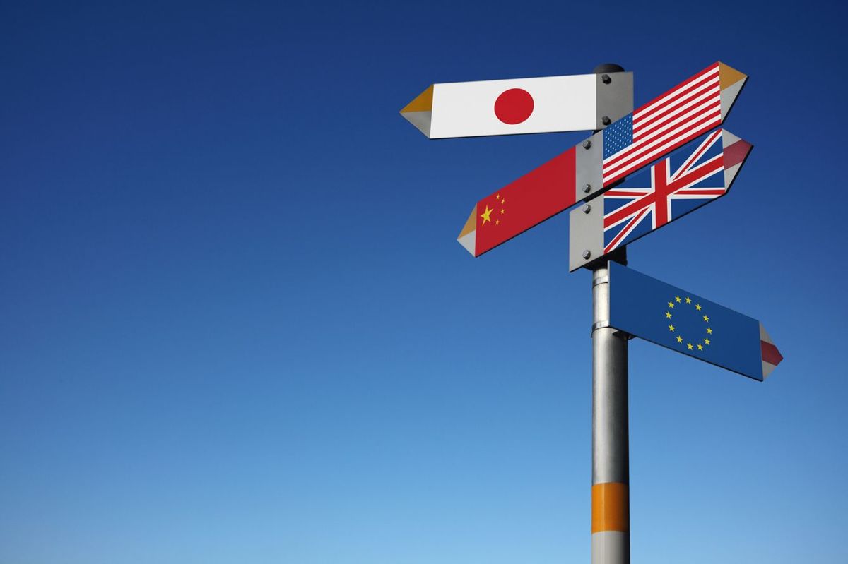 日本、中国、アメリカ、イギリス、EUのそれぞれの国旗がそれぞれの方向を指している道標
