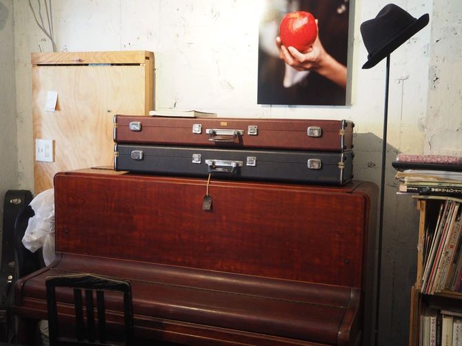茶色いアップライトピアノ、黒いハット、真っ赤なリンゴの写真