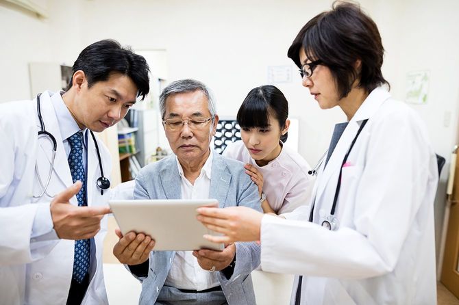 Doctors discussing with senior man while using digital tablet