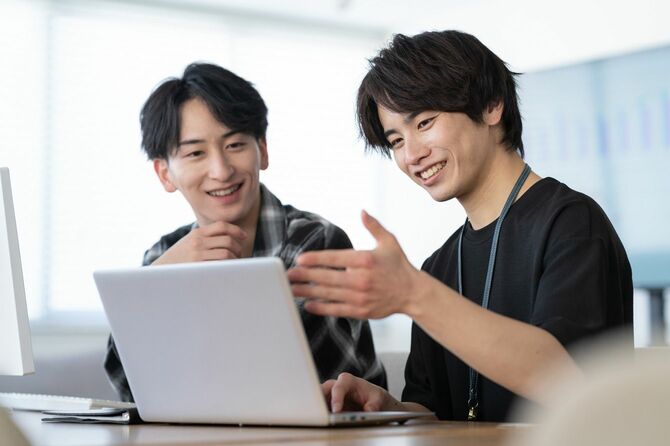 オフィスで同僚の相談に乗る若い男性エンジニア