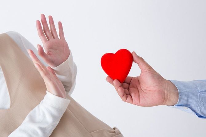 ハート形のオブジェを差し出す男性と拒否している女性