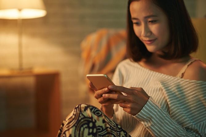 ソファに座ってスマホを見る女性