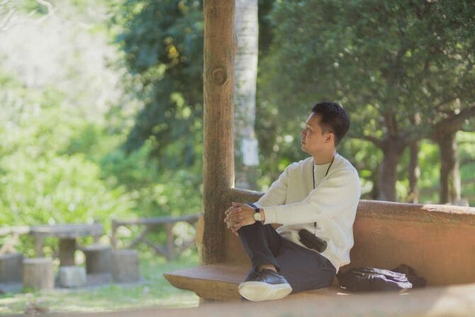 木のそばのベンチで休む男性