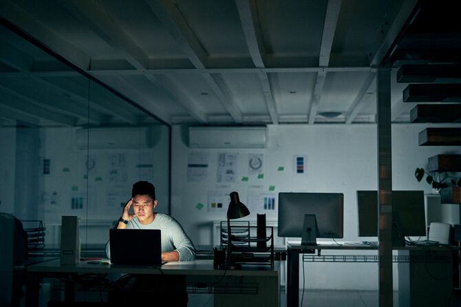 深夜のオフィスで一人残業をする男性