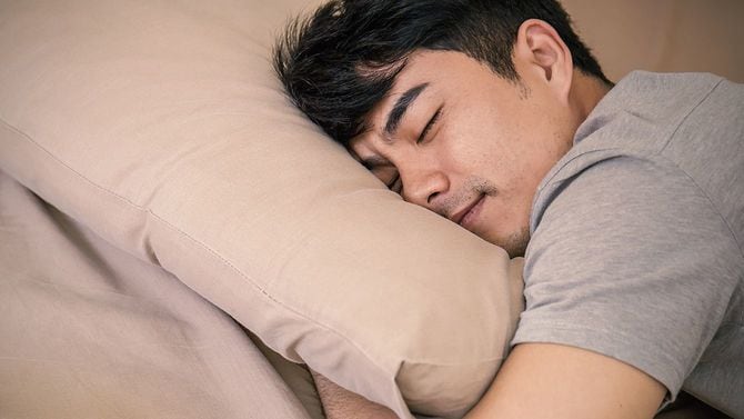 枕を抱えて眠る男性