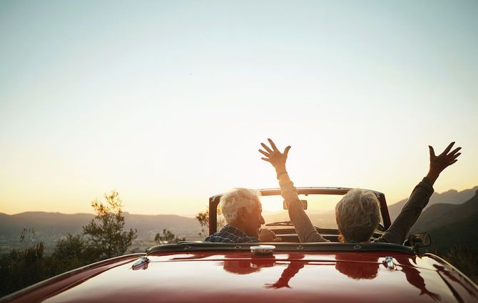 オープンカーでドライブをする老夫婦