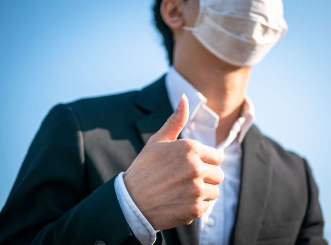 マスクを着用してサムズアップする男性