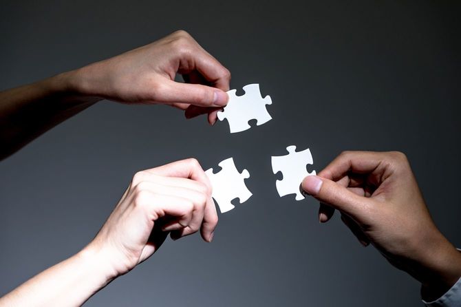 ジグソーパズルを持つ3人の手