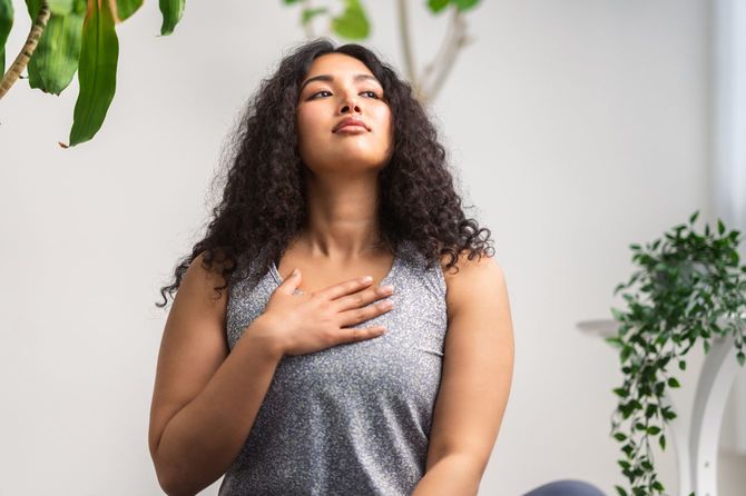 胸に手をあてて、深呼吸している女性