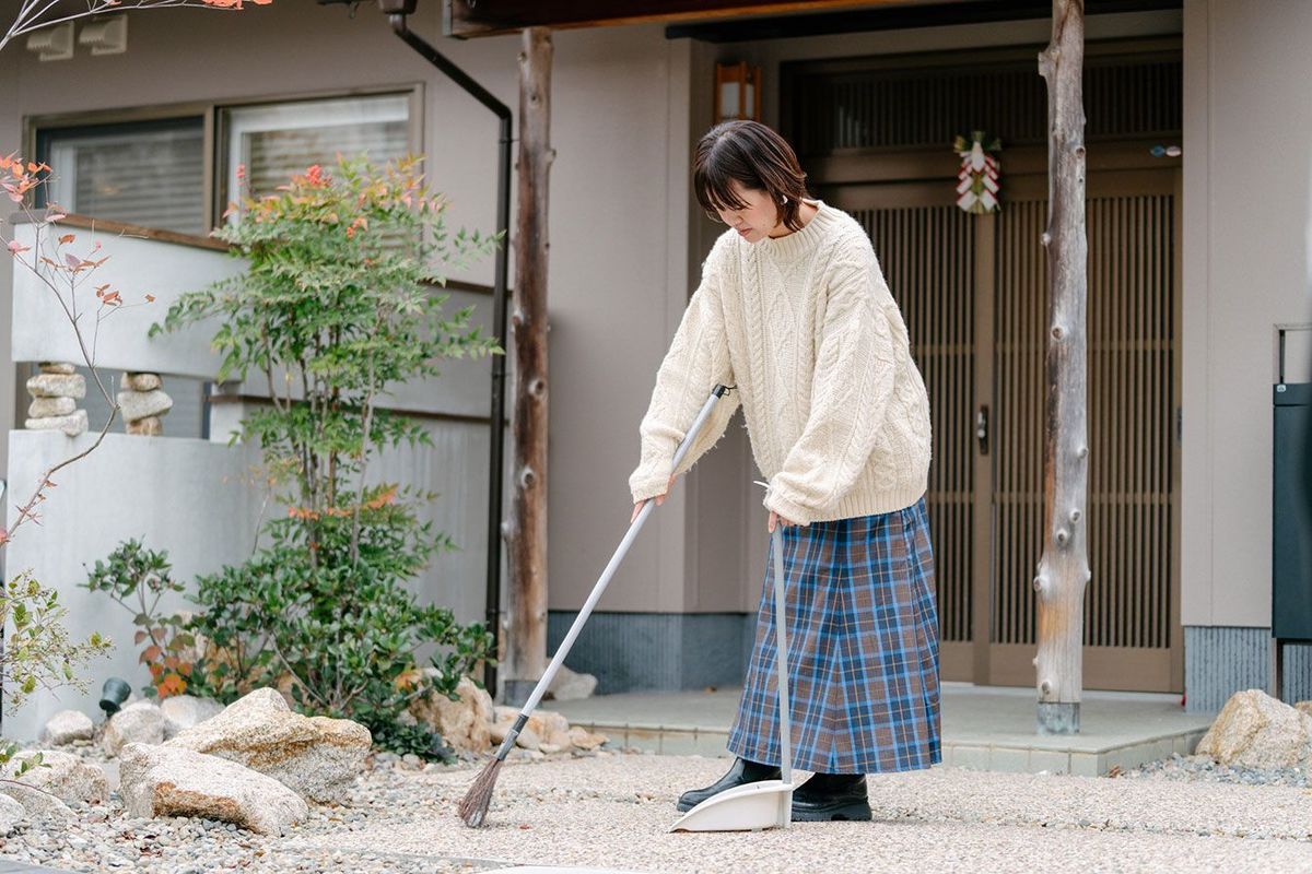 玄関前を掃除する女性