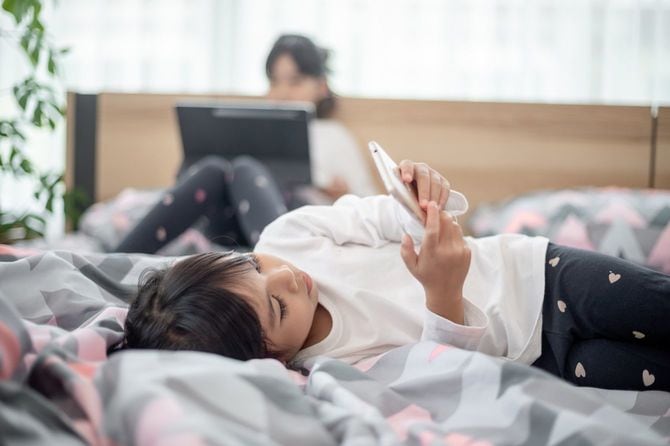ベッドの上でスマホを見ている子
