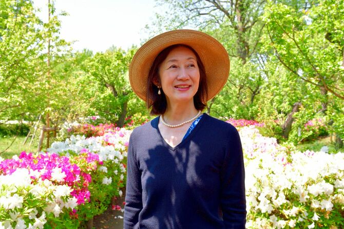 満開のツツジが咲く公園を歩く女性