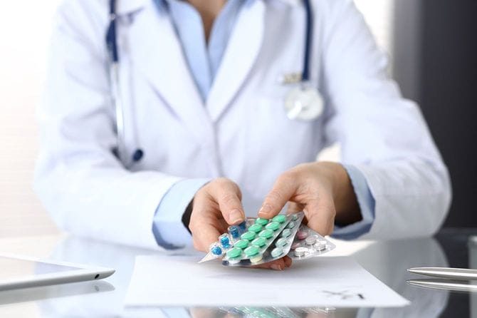 数種類の薬を手に持っている医師