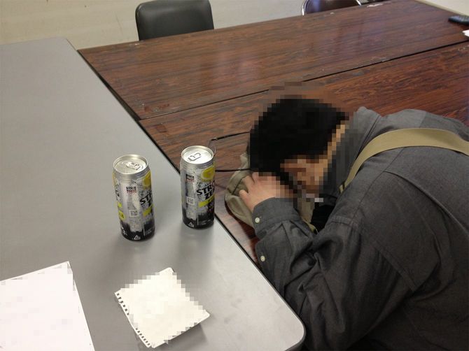 机に顔を伏せる男性