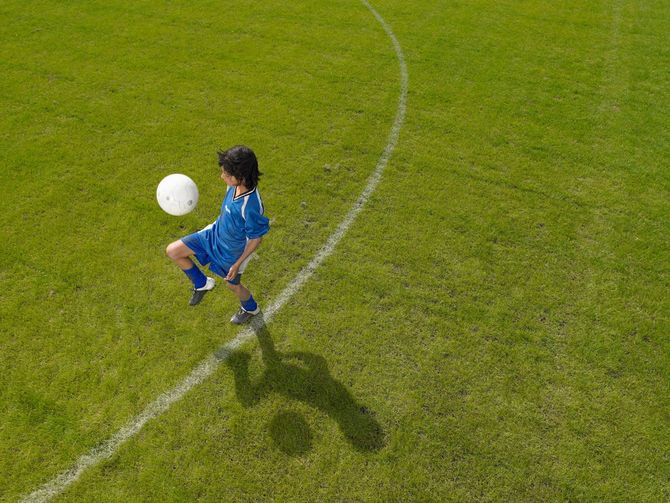 グラウンドでリフティングする少年