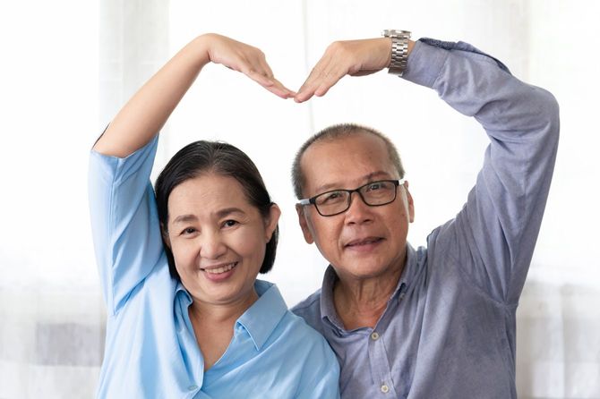 腕でハートマークを表現するシニア夫婦