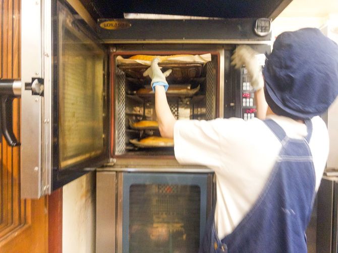 オーブンから明太フランスを取り出すスタッフ