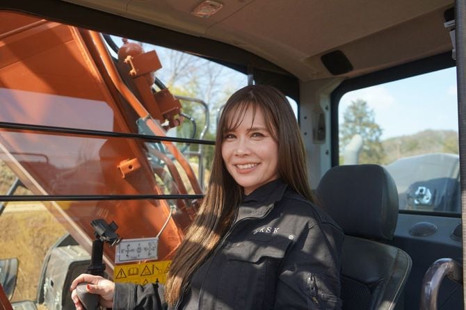 20トンのユンボの操縦室に乗る東さん。このサイズのユンボには屋根付きの操縦室があるが、比較的小さいユンボになると写真にあるような室内が無いものが多いという