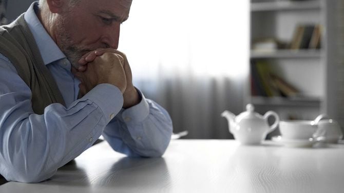 ハード思考、うつ病を持っている台所のテーブルに座っている年配の紳士