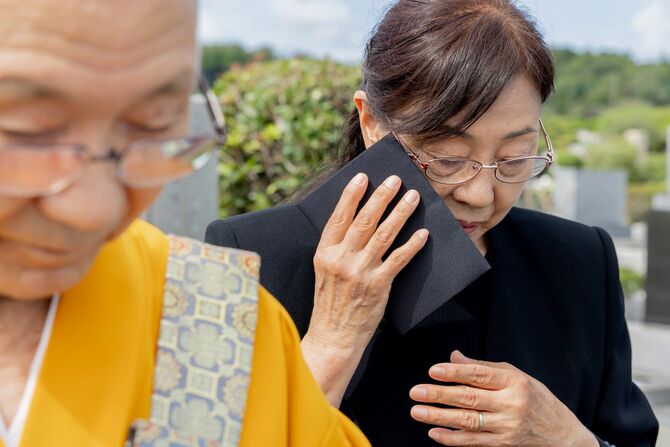 墓前の僧侶と遺族