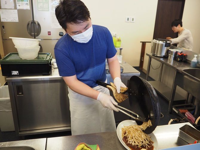 ステーキに大量のもやしをトッピングする大曽根さん